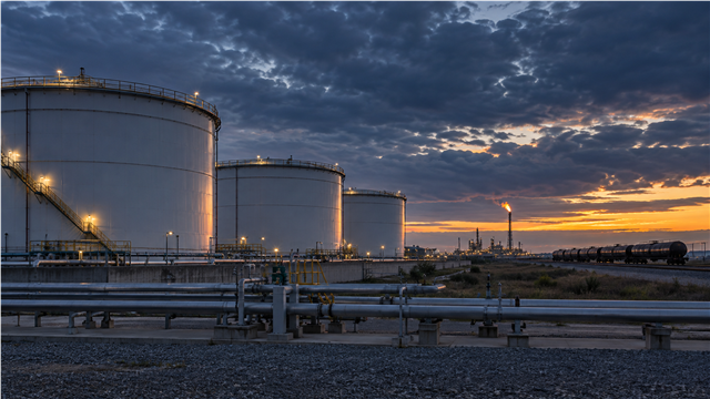 Terminal de almacenamiento de petróleo con depósitos y vagones cisterna al amanecer